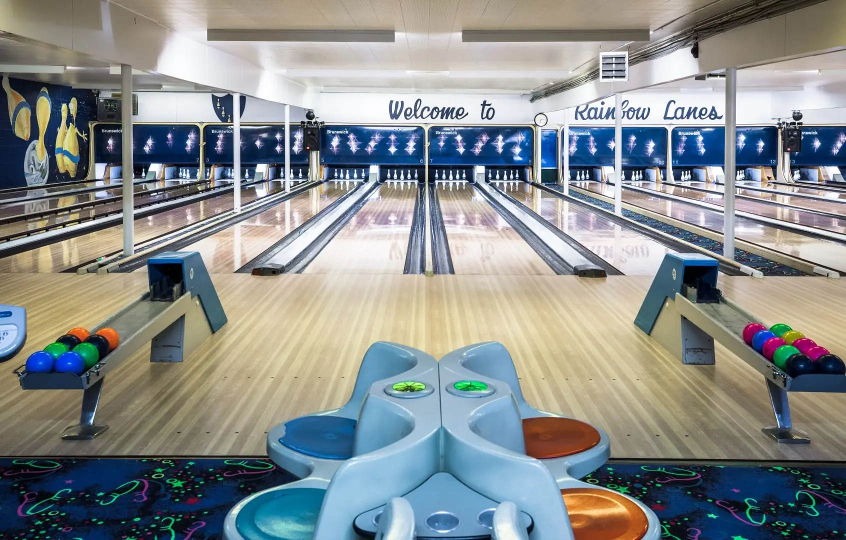 The lanes at Rainbow Lanes under house lights, ball racks and scoring consoles in the foreground.
